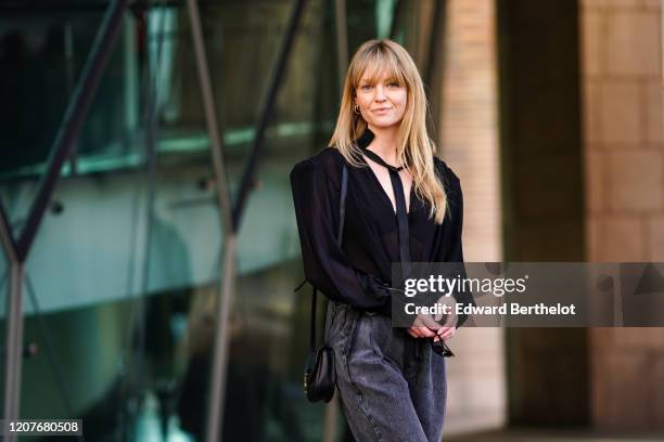 Jeanette Madsen wears a black shirt, a Saint Laurent YSL bag, gray denim large pants, outside Vivetta, during Milan Fashion Week Fall/Winter...