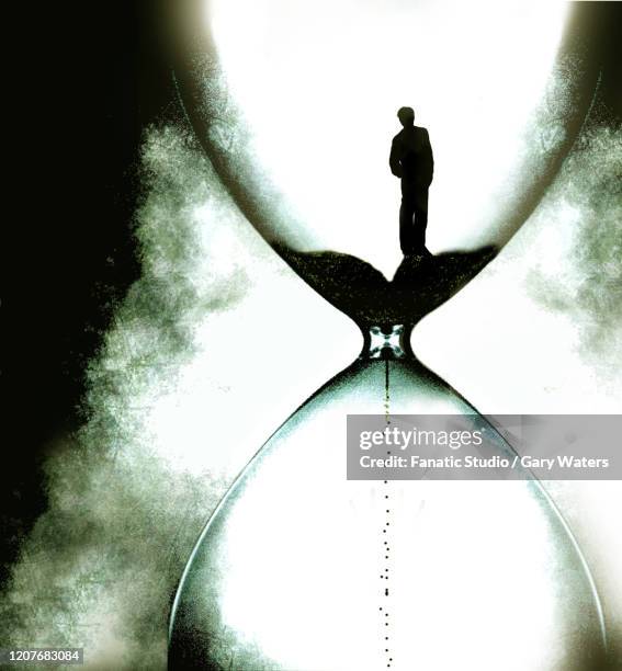 stockillustraties, clipart, cartoons en iconen met concept image of a man in a hourglass looking down at the disappearing sand depicting time running out - time out silhouettes