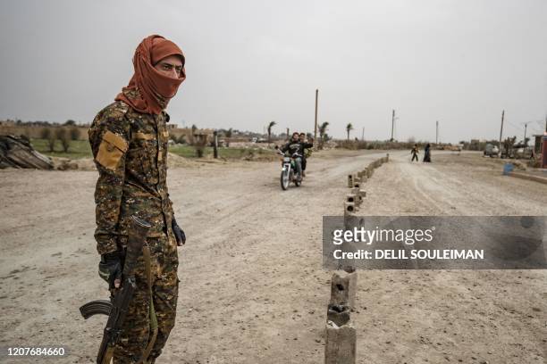 Fighter of the Syrian Democratic forces stands guard at the entrance of the eastern Syrian village of Baghouz on March 13 a year after the fall of...