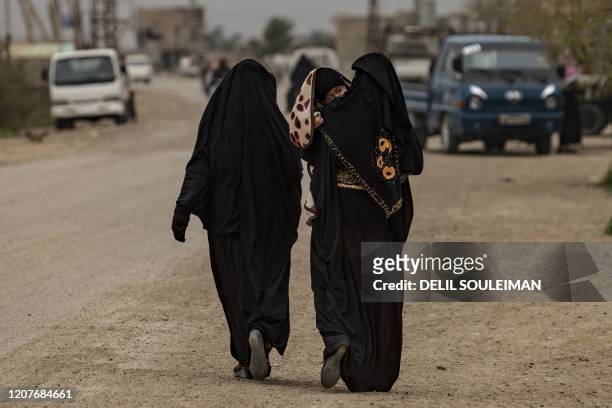 Burqa-clad women walk in the eastern Syrian village of Baghouz on March 13 a year after the fall of the Islamic State's caliphate. - A year after the...