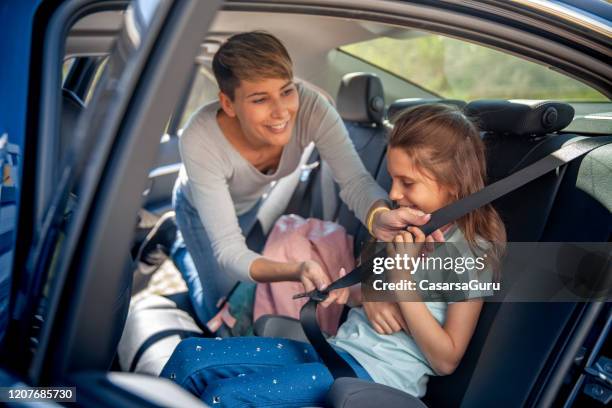 mãe gostando de ajudar filha a apertar seu cinto de segurança - vehicle seat - fotografias e filmes do acervo