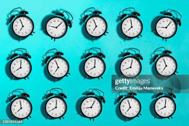 black alarm clock on blue background - perder el tiempo fotografías e imágenes de stock