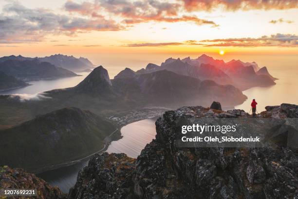 luchtmening van mens die zich op bergpiek op eiland senja bevindt - midnight sun norway stockfoto's en -beelden