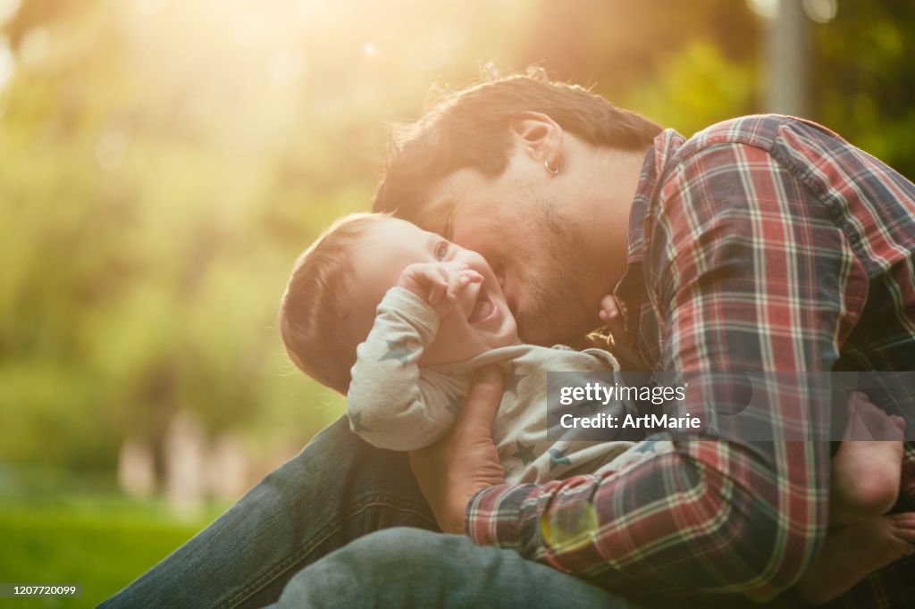 De jongen van de baby met is vader die van de de zomerdag geniet