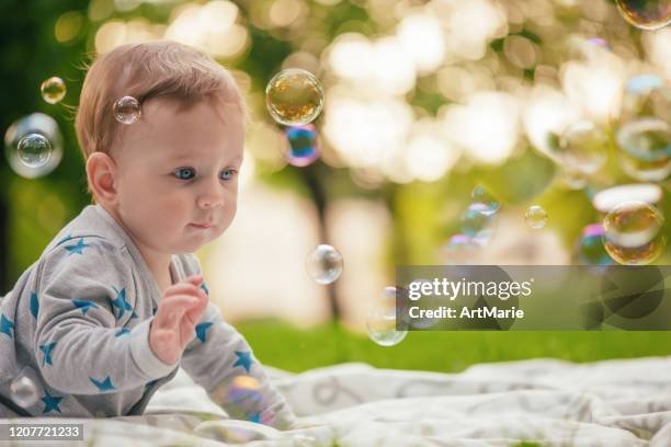 baby boy looking at bubbles in summer park - catching bubbles stock pictures, royalty-free photos & images