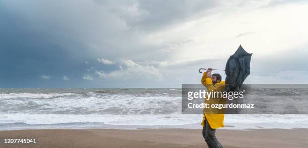 man on stormy beach - climate disaster stock pictures, royalty-free photos & images