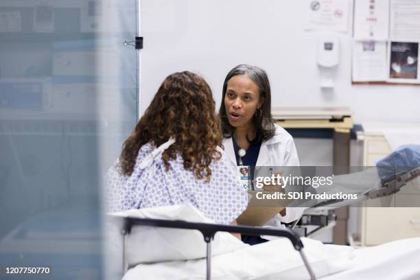 in emergency room, mature doctor has serious conversation with teen - hospital gown stock pictures, royalty-free photos & images