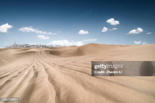 empty desert with tire track and city horizon under clear sky - ad oasis stock pictures, royalty-free photos & images