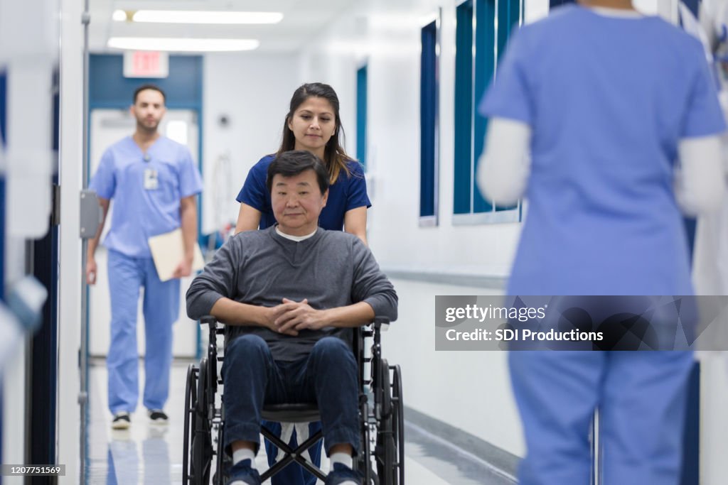 Nurse pushes patient in wheelchair