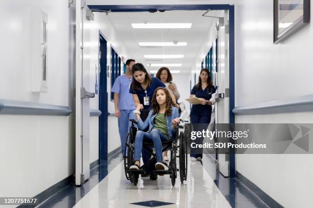 worried girl holds nurse's hand while in wheelchair - leaving hospital stock pictures, royalty-free photos & images