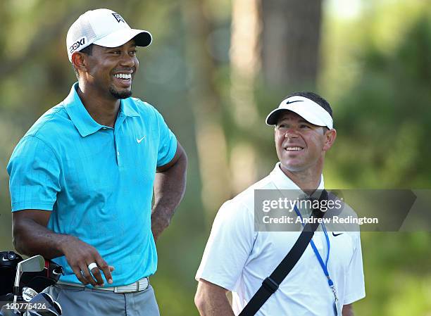 Tiger Woods waits with swing coach Sean Foley during a practice round prior to the start of the 93rd PGA Championship at the Atlanta Athletic Club on...