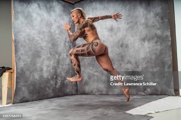 Portrait of Olympic bobsledder Kaillie Humphries as she jumps, showing the tattoos on his arms, torso, and legs, Los Angeles, California, July 15,...