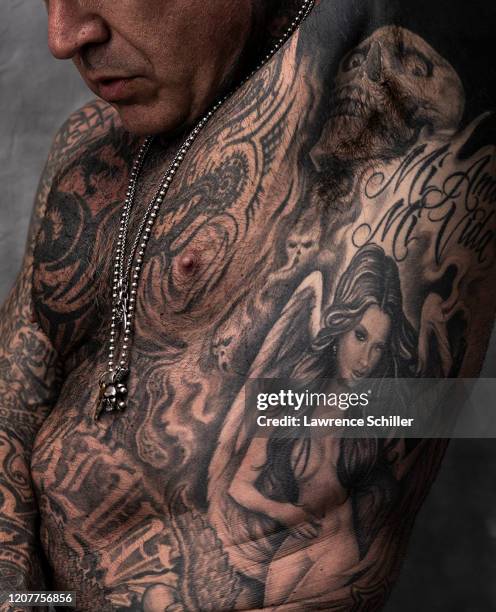 Close-up of Evan Seinfeld as he shows the tattoos on his chest and torso, Los Angeles, California, July 16, 2019. He wears a portrait of his wife...