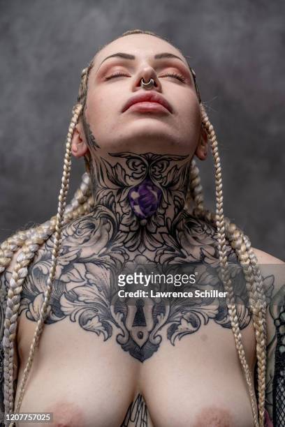 Portrait of Alicia Mecca, her head titled back, as she shows the tattoos on her face, neck, and chest, New York, New York, June 21, 2019. She wears...