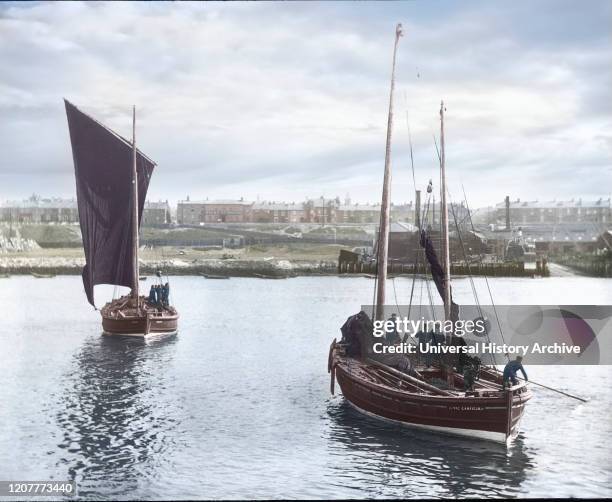 Magic lantern slide circa 1880, Victorian/Edwardian Social History. Two fishing boats leaving harbour with South Shields town in the background....