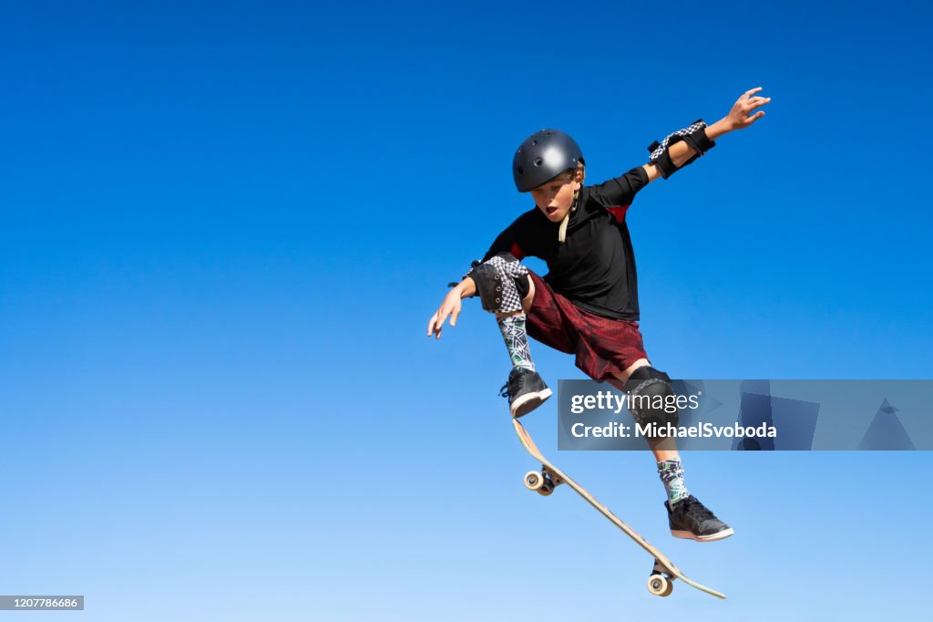 Young Boy auf einem Skateboard Jumping Into The Air