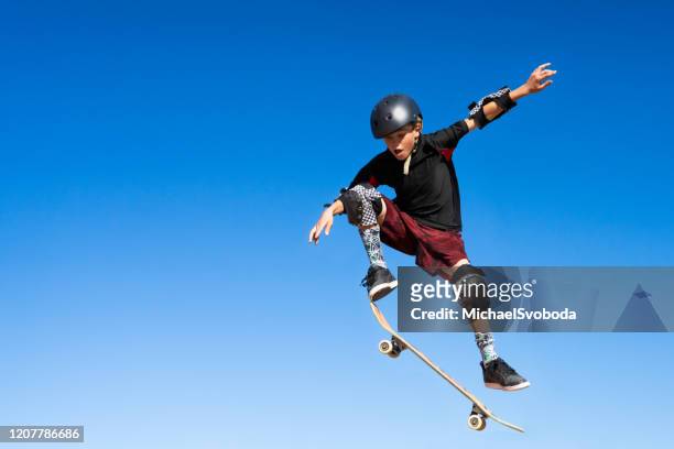 young boy on a skateboard jumping into the air - skating stock pictures, royalty-free photos & images