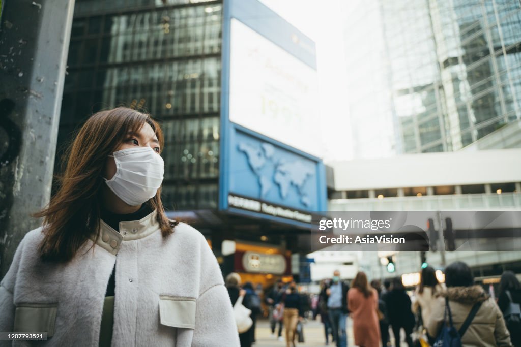 Young Asian woman wearing a protective face mask to prevent the spread of germs and viruses in the city