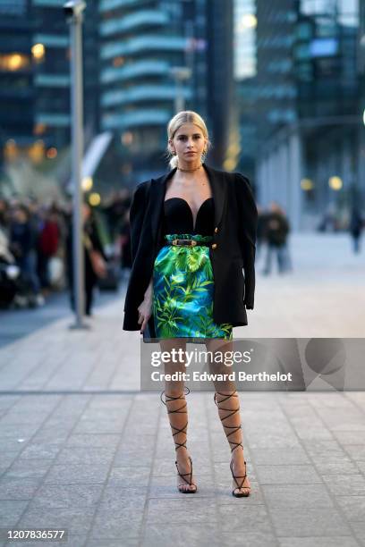 Caroline Daur wears a necklace, earrings, a black oversized blazer jacket, a black bustier top, a belt, a green and blue floral print lustrous silky...