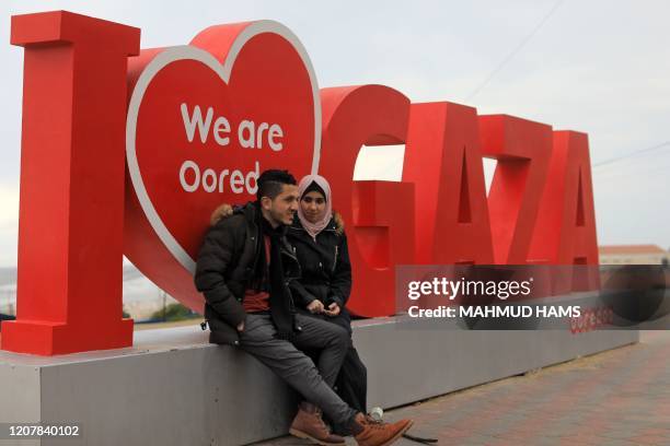 Palestinian groom Ahmed al-Ketnani sits with his 19-year-old fiancee Sara along the beach next to a sign reading "I Love Gaza", in Gaza City on March...