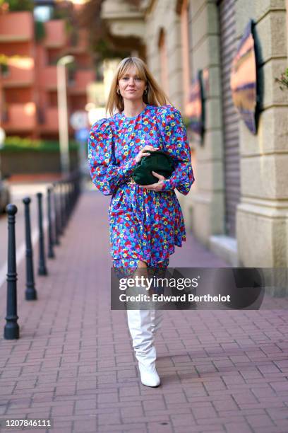 Jeanette Madsen wears a multicolor floral print dress, a green bag, a belt, white high boots, outside Marni, during Milan Fashion Week Fall/Winter...