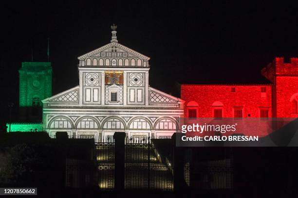 General view taken on March 20, 2020 in Florence shows the Basilica di San Miniato al Monte illuminated with the colors of the Italian flag, during...