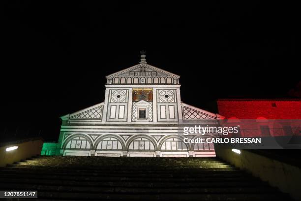 General view taken on March 20, 2020 in Florence shows the Basilica di San Miniato al Monte illuminated with the colors of the Italian flag, during...