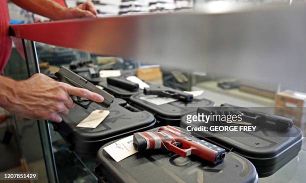 Worker restocks handguns at Davidson Defense in Orem, Utah on March 20, 2020. - Gun stores in the US are reporting a surge in sales of firearms as...