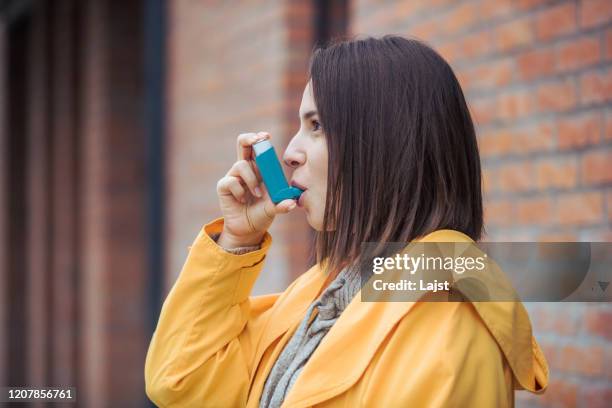 young woman using asthma inhaler - asthma-inhaler-spray stock pictures, royalty-free photos & images