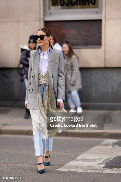 Olivia Palermo wears sunglasses, a purple/white striped shirt, a gray oversized blazer jacket, blue and white striped pants, green shoes, a lace...