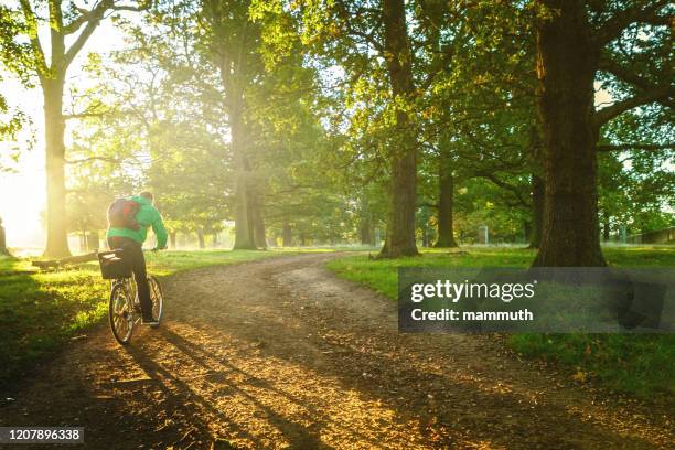 joven ciclismo en richmond park, londres - richmond upon thames fotografías e imágenes de stock