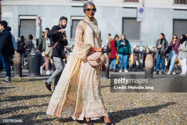 Model Halima Aden wears a floral headscarf, oversized sunglasses, a pink Etro bag, and tan Etro print dress at the Etro show during Milan Fashion...