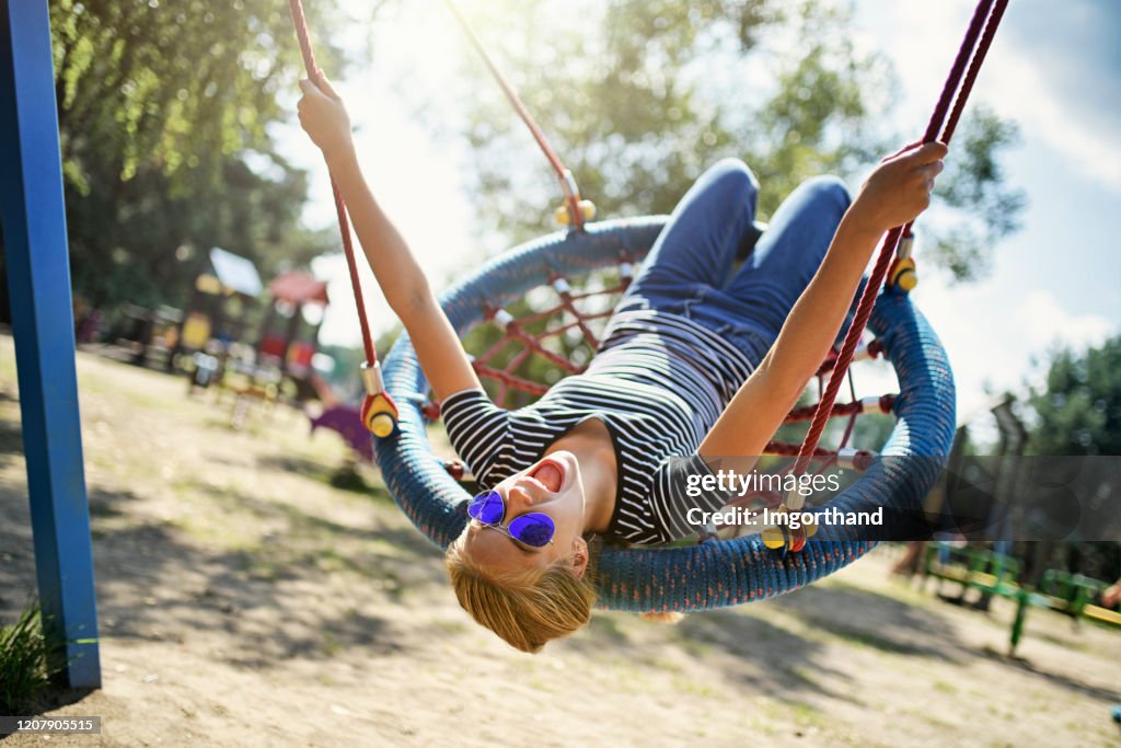 Teenage girl enjoying swinging at the playground