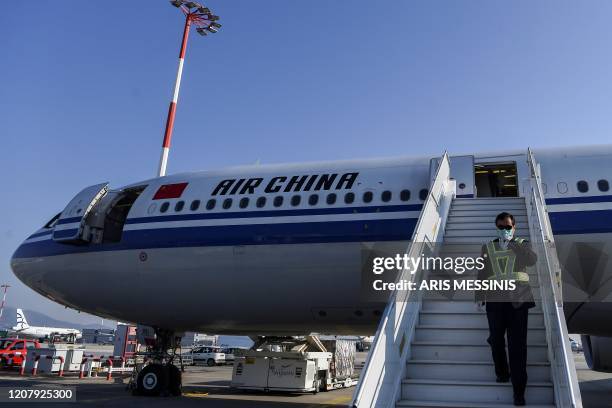 Member of staff, wearing a facemask for protective measures, disembarks from an Air China airbus carrying 500.000 protective masks at the Athens...