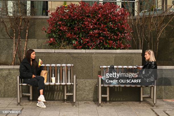 Two friends enjoy their lunch together at a safe distance in central Leeds on March 21 a day after the British government said it would help cover...