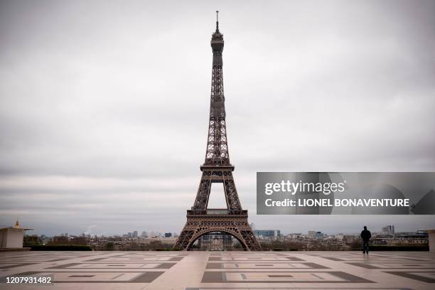 Man walks on the deserted Trocadero square in front of the Eiffel Tower on March 21, 2020 in Paris on the fifth day of a strict nationwide lockdown...