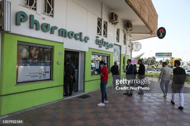 Tunisians queue in front of a pharmacy as they respect the safety distance to prevent the coronavirus COVID-19 in the town of Ariana, Northern...
