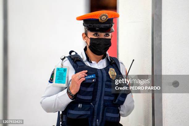 Police officer wears a face mask at Benito Juarez International airport, in Mexico City, on March 21, 2020. - International flights keep operating in...