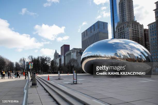 People visit a closed off Cloud Gate statue, known as the "Bean", in Millennium Park in Chicago, Illinois, on March 21, 2020. - Almost one billion...