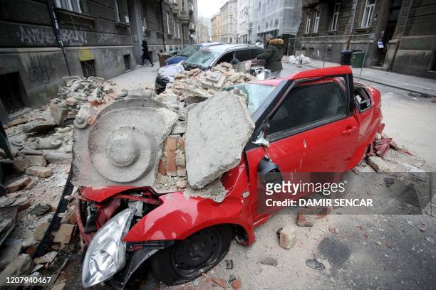 Photograph taken on March 22, 2020 shows a car destroyed by building rubbles in the streets of downtown Zagreb, after an earthquake hit the country...
