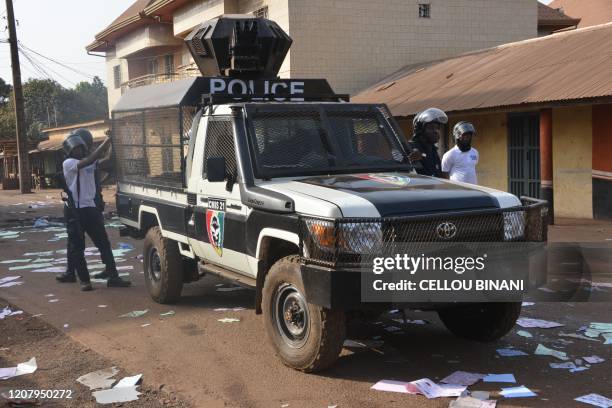 Guinean police officers stand next to ballot papers on the ground outside the polling station in Conakry on March 22, 2020 during a constitutional...