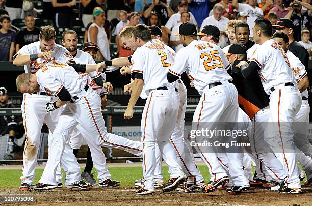 Nolan Reimold of the Baltimore Orioles is mobbed by teammates after hitting the game winning home run in the tenth inning against the Chicago White...