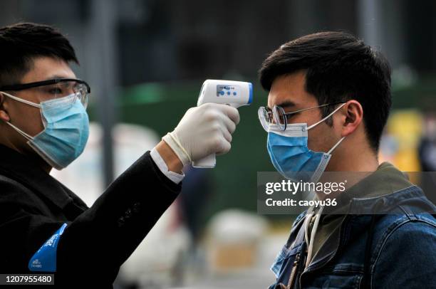 indossando maschere, persone in fila per i controlli della temperatura prima di entrare nel centro commerciale , starbacks e hotel a chengdu, cina - china coronavirus foto e immagini stock