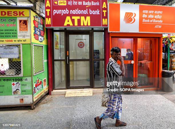 Man walks past a Punjab National Bank and Bank of Baroda ATM in Kolkata.