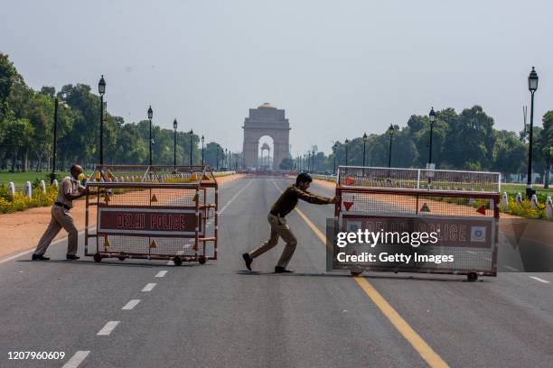 Indian policemen push barricades to place them in the center of a a road leading to historic India Gate, during a one-day nationwide Janata curfew...
