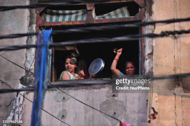 People make noise with kitchenware utensils and clap in a balcony to thank essential service providersduring a one-day Janata curfew imposed by the...