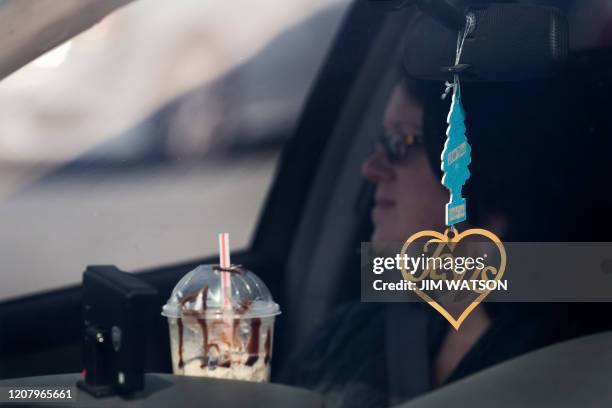 Jesus heart pendant hangs from the rearview mirror as a member of Jesus' Church listens from her car during a Sunday church service heldat Great...