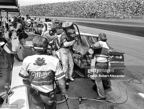 Driver Bobby Allison is serviced by his crew members during a pit stop at the 1987 Pepsi Firecracker 400 race at Daytona International Speedway in...