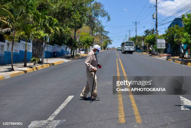 An elderly man wearing a protective mask walks through the streets on March 22, 2020 in San Salvador, El Salvador. Three cases of COVID-19 has been...