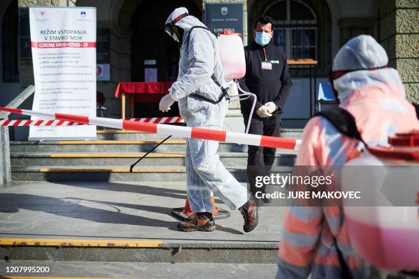 Workers wearing protective clothes disinfect entrance of the Town Hall in Kranj, Slovenia, on March 23, 2020 amid concerns over the spread of the...